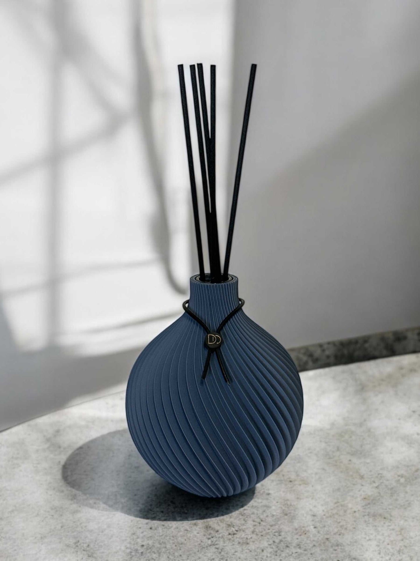 Elegant 3D printed globe-shaped diffuser with black reeds on a marble surface.