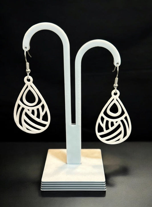 Boucles d'oreilles Dropa en forme de goutte ajourée, design élégant et moderne, fabriquées en PLA biosourcé avec attache en argent, sur support d'exposition.