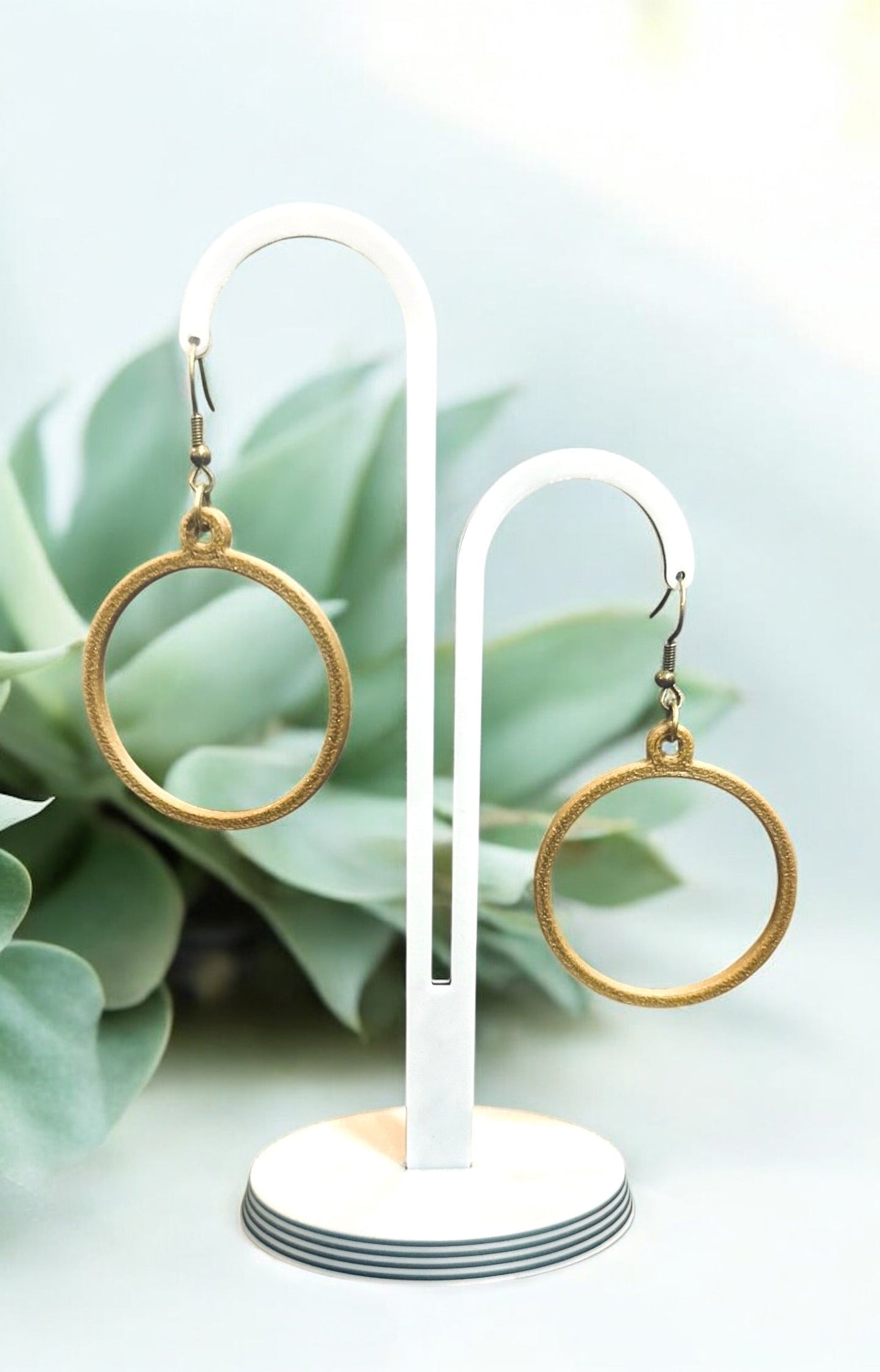 Boucles d'oreilles créoles en matériau éco-responsable, légères et brillantes, sur support blanc.