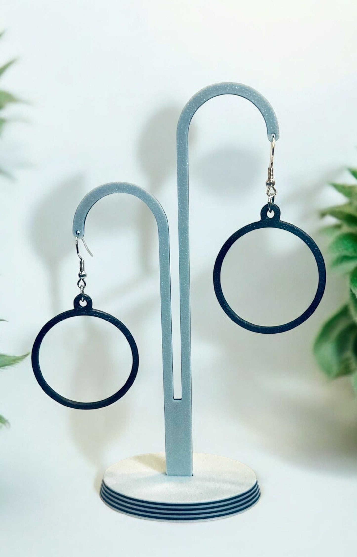 Boucles d'oreilles créoles modernes et légères sur un présentoir, finition brillante, design circulaire, fabriquées en PLA, éco-responsables.