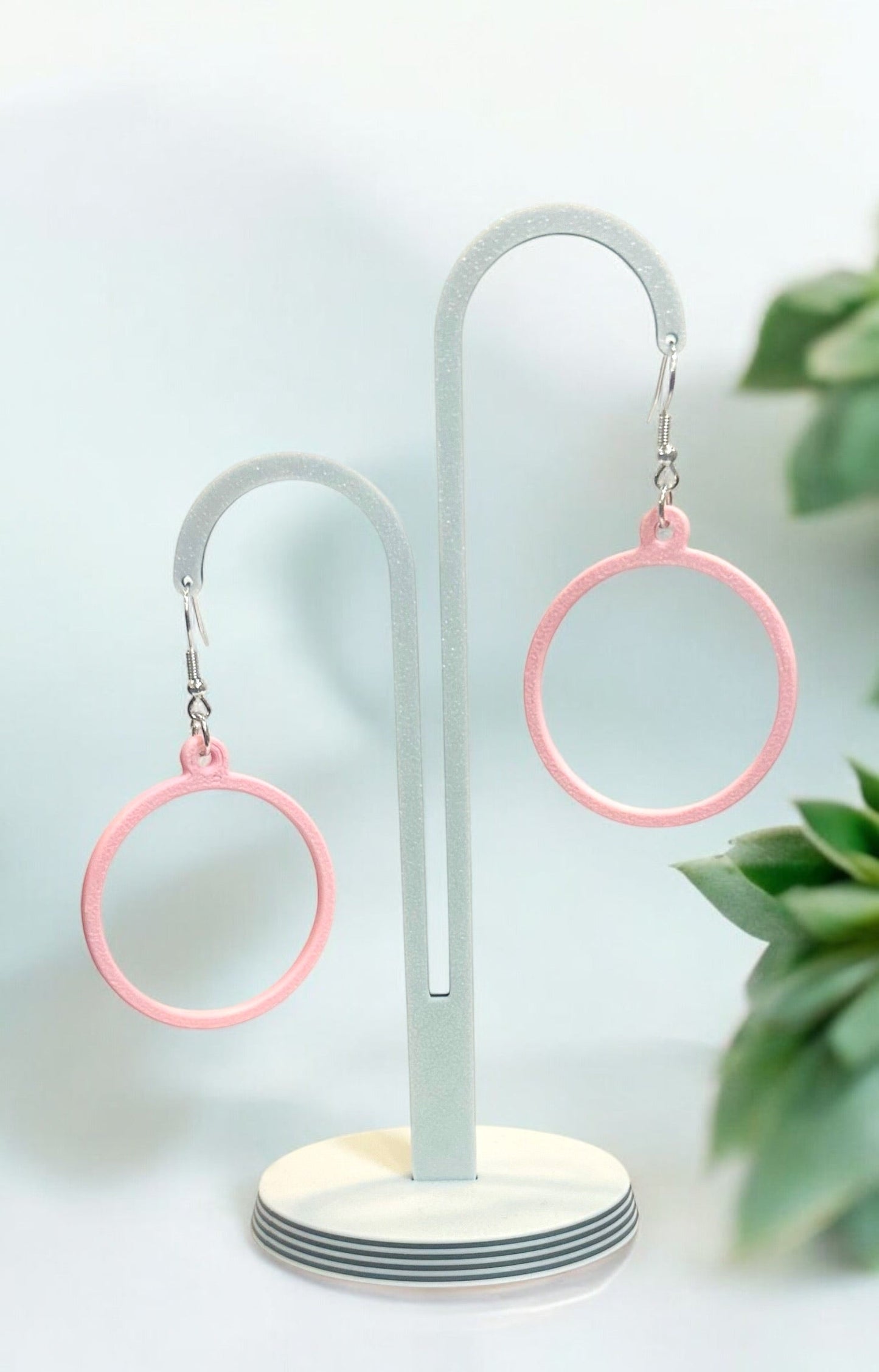 Boucles d'oreilles créoles roses sur support, finition brillante, légères et éco-responsables.