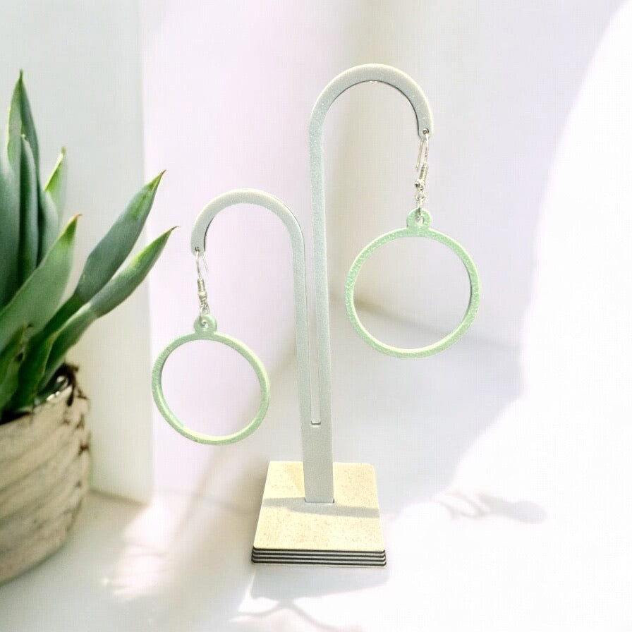 Boucles d'oreilles Créoles en PLA biosourcé, légères et scintillantes, sur présentoir, avec attache en argent.