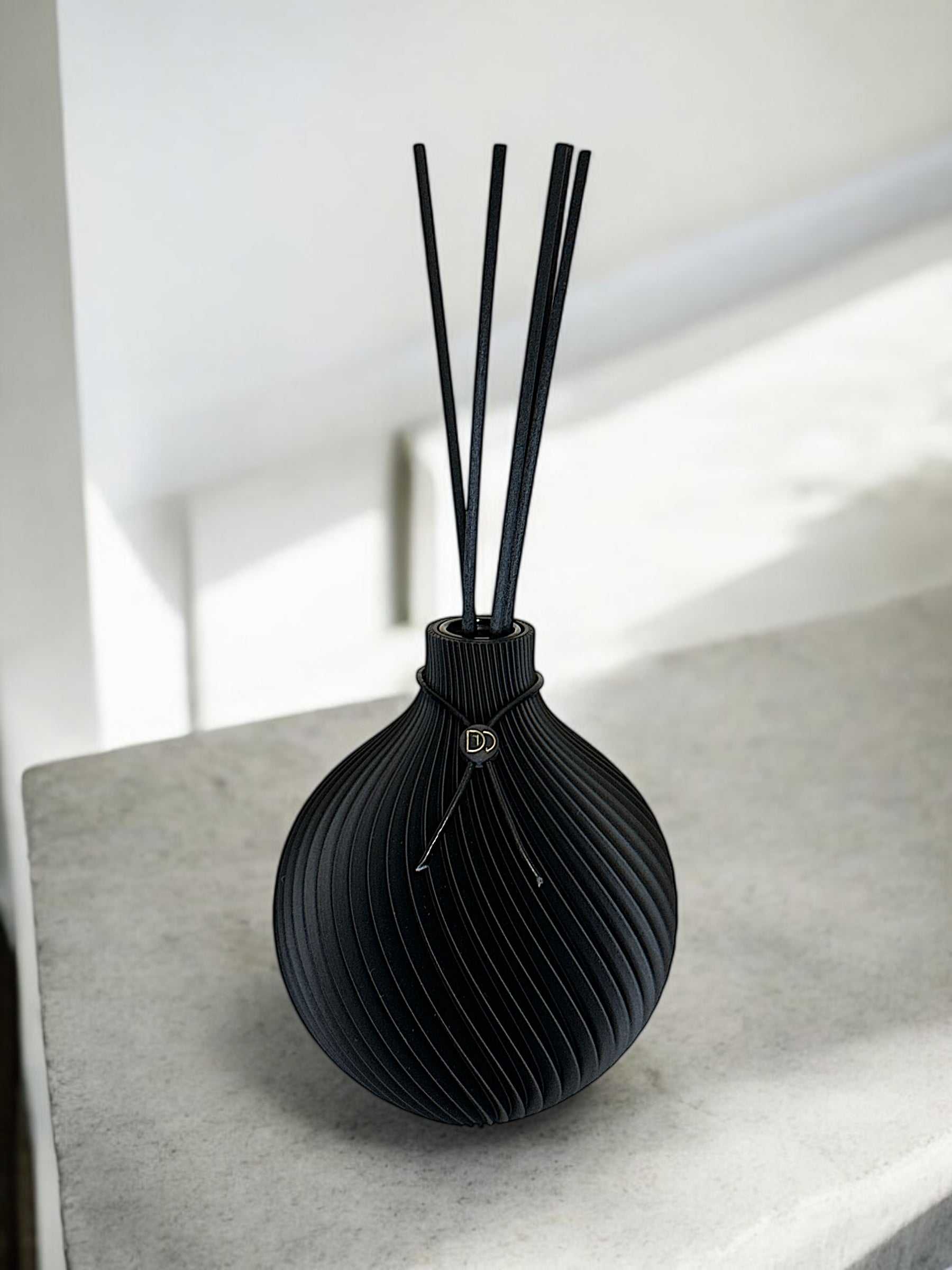 Élégant diffuseur de parfum en forme de globe noir sur une surface blanche, 3D imprimé pour une ambiance raffinée.