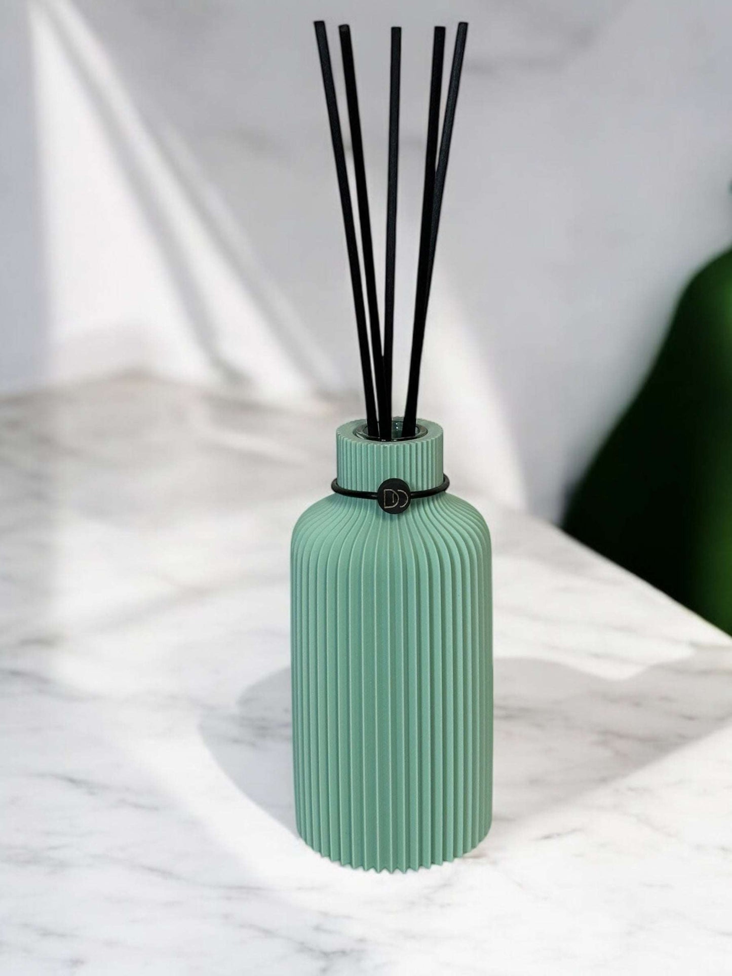 Minimalist design diffuser with elegant 3D-printed bottle and reed sticks on marble surface.