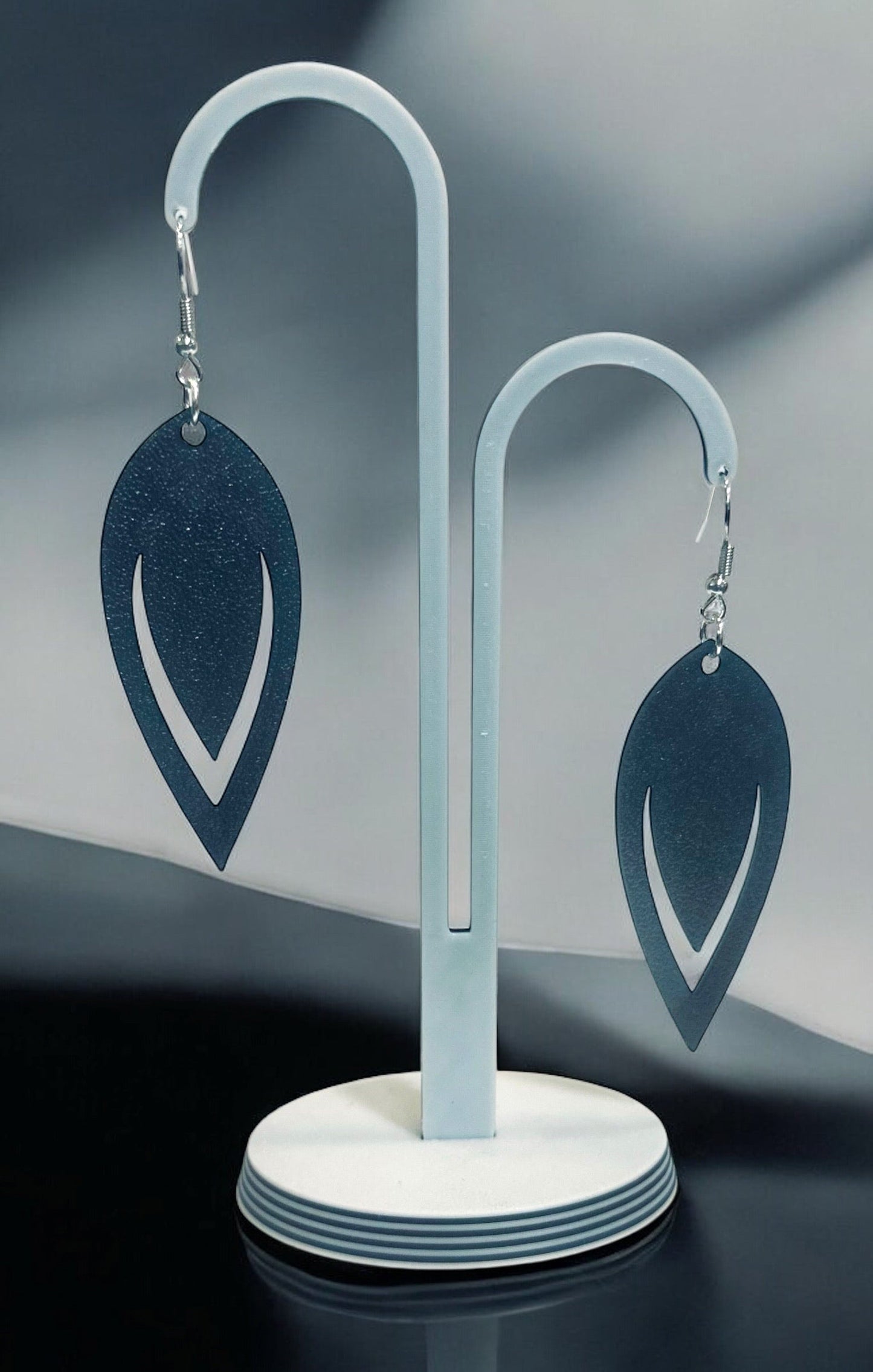Boucles d'oreilles Luma en forme de goutte ajourée avec finition bronze, suspendues sur un présentoir blanc.