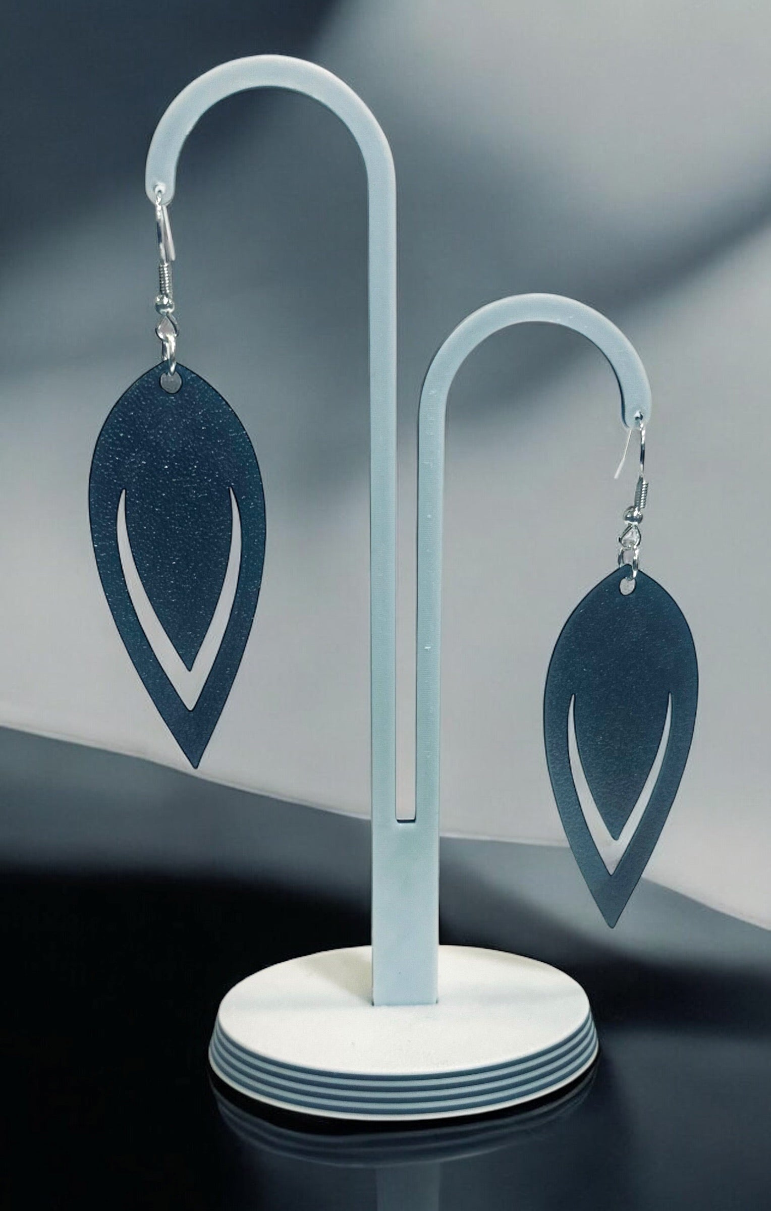 Boucles d'oreilles Luma en forme de goutte ajourée avec finition bronze, suspendues sur un présentoir blanc.