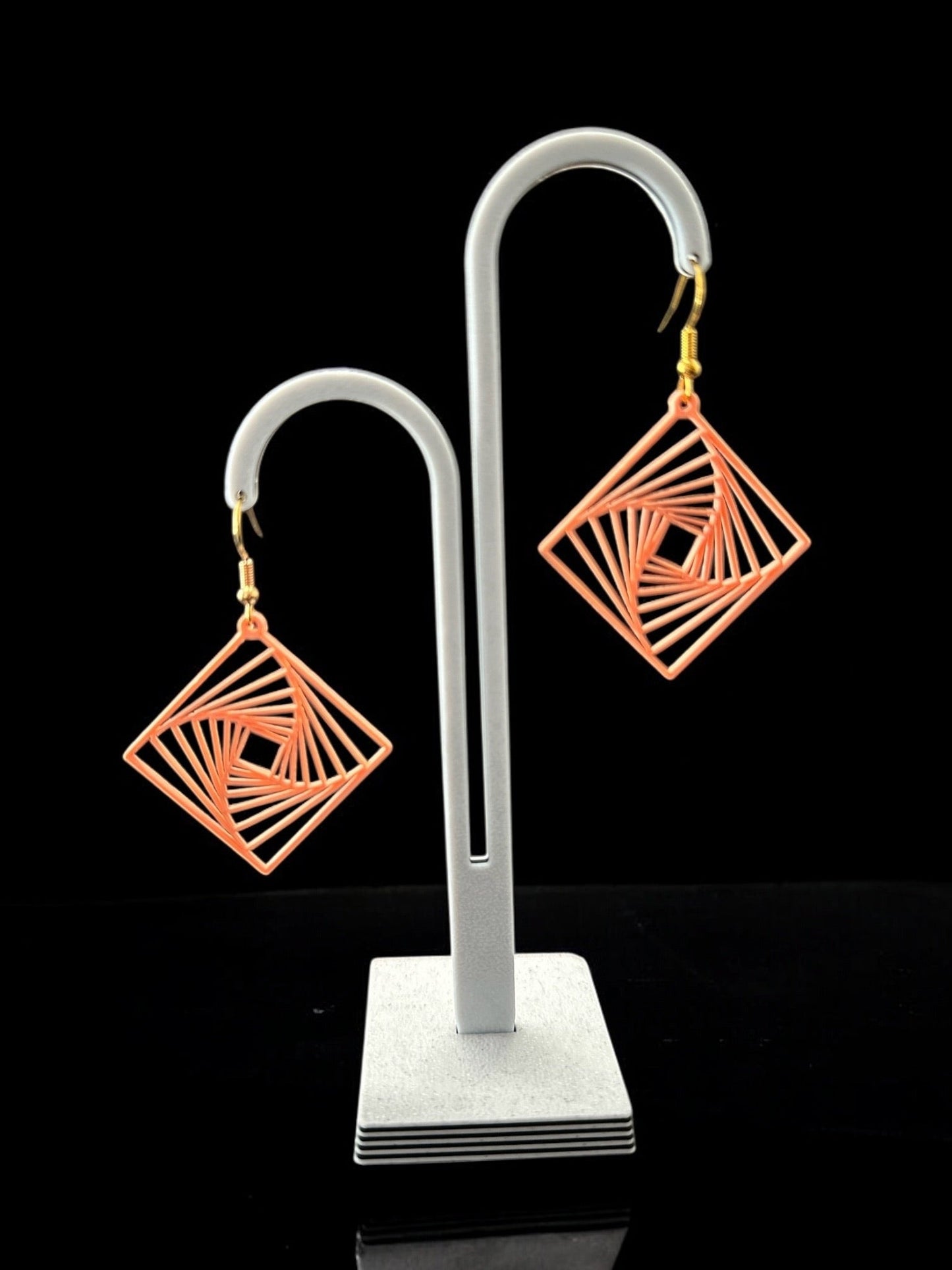 Boucles d'oreilles Twina en losange ajouré, design spirale géométrique, finition ivoire, attaches argentées, sur présentoir.
