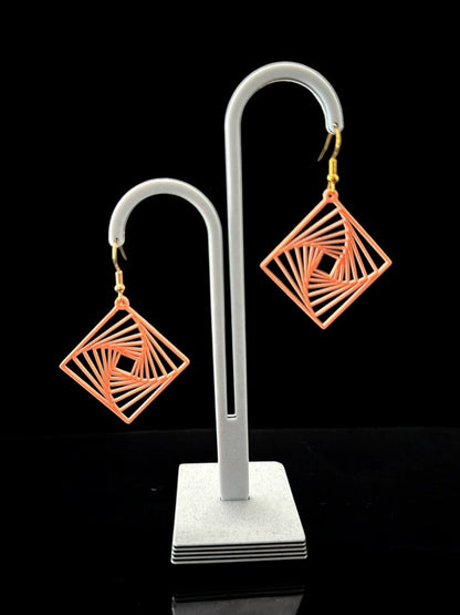 Boucles d'oreilles Twina en losange ajouré, design spirale géométrique, finition ivoire, attaches argentées, sur présentoir.