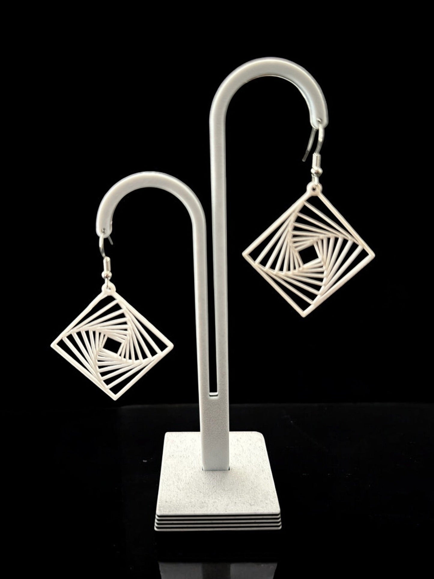 Boucles d'oreilles Twina ivoire, design losange ajouré et hypnotique, finition moderne et élégante.